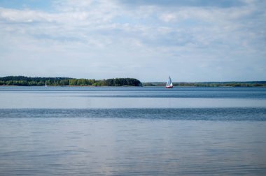 Yaz manzarası tatlı su deposu ve uzaktaki yelkenli.
