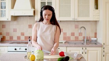 Genç bayan taze sebzeleri pişirmek için hazırlıyor.