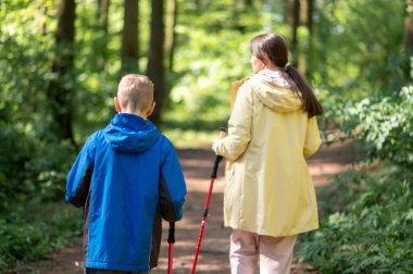 Anne ve 11 yaşındaki oğlunun, güneşli bir orman patikasında Kuzey Kutbu 'nda yürüyüş yaparken görüntüsü.