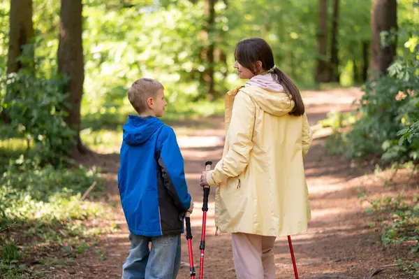 Anne ve 11 yaşındaki oğlunun, güneşli bir orman patikasında Kuzey Kutbu 'nda yürüyüş yaparken görüntüsü.