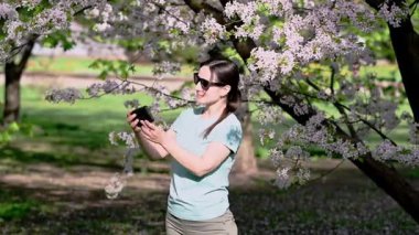 Bir kadın çiçek açan bahar parkında dokulara hapşırıyor, polen alerjisinden muzdarip.