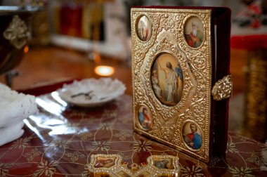 Ortodoks kilisesinde kilisenin masasındaki altın haç ve diğer kilise gereçleri vaftiz törenine hazırlanıyor.