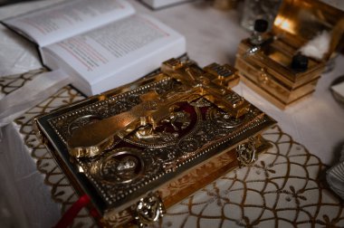Ortodoks kilisesinde kilisenin masasındaki altın haç ve diğer kilise gereçleri vaftiz törenine hazırlanıyor.