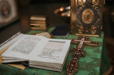 Ortodoks kilisesinde kilisenin masasındaki altın haç ve diğer kilise gereçleri vaftiz törenine hazırlanıyor.