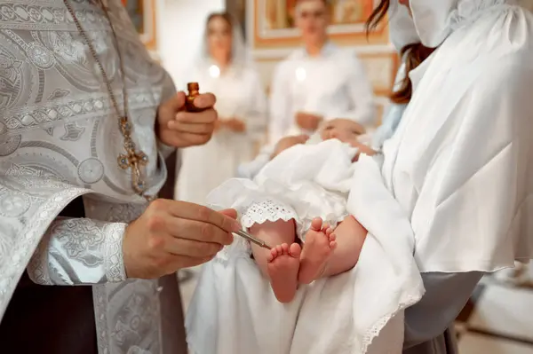 Bir rahip, Ortodoks vaftiz töreninde bebeğin ayaklarını yağ ile yağlar.
