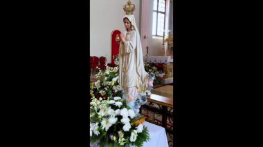 Güzel dekore edilmiş bir kilise sunağının önünde bir buket taze çiçekle Bakire Meryem heykeli bağlılığı, saflığı ve inancı simgeliyor.
