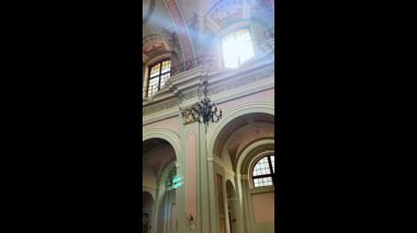 Güzel bir Katolik kilisesinin penceresinden süzülen güneş ışığı kutsal iç mekanı hafifçe aydınlatıyor ve mimari detayları vurguluyor.