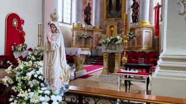 Güzel dekore edilmiş bir kilise sunağının önünde bir buket taze çiçekle Bakire Meryem heykeli bağlılığı, saflığı ve inancı simgeliyor.