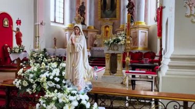 Güzel dekore edilmiş bir kilise sunağının önünde bir buket taze çiçekle Bakire Meryem heykeli bağlılığı, saflığı ve inancı simgeliyor.