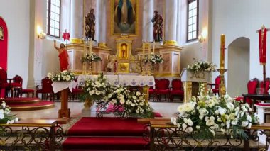Katolik katedralinde güzel dekore edilmiş bir sunak. Taze çiçekler, mumlar ve geleneksel dini öğelerle süslenmiş. Huzurlu ve kutsal bir atmosfer yaratıyor.
