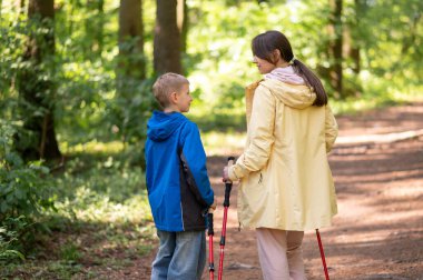 Anne ve 11 yaşındaki oğlunun, güneşli bir orman patikasında Kuzey Kutbu 'nda yürüyüş yaparken görüntüsü.