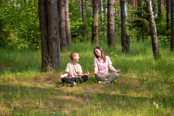 Anne ve oğlu nilüfer çiçekleri içinde meditasyon yapıyor ve gülüyor. Orman çayırlarında poz veriyor, birlikte doğanın ve zamanın tadını çıkarıyor.