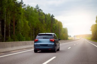 Gün batımında ağaçlar ve huzurlu bir akşam ışığı ile çevrili bir ormanda araba sürüyor.