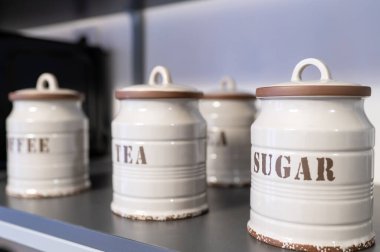 Seramik kavanozlarda kahve, çay, rafa konmuş şeker, klasik mutfak dekorasyonu.