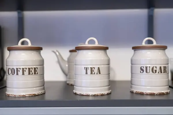 Seramik kavanozlarda kahve, çay, rafa konmuş şeker, klasik mutfak dekorasyonu.