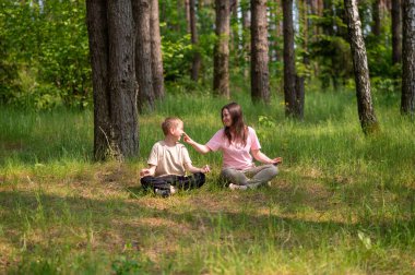 Anne ve oğlu nilüfer çiçekleri içinde meditasyon yapıyor ve gülüyor. Orman çayırlarında poz veriyor, birlikte doğanın ve zamanın tadını çıkarıyor.