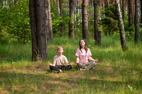 Anne ve oğlu nilüfer çiçekleri içinde meditasyon yapıyor ve gülüyor. Orman çayırlarında poz veriyor, birlikte doğanın ve zamanın tadını çıkarıyor.