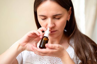 Alerji ya da tıkanıklıktan kurtulmak için burun spreyi kullanan genç kadın, konsept: evde tedavi