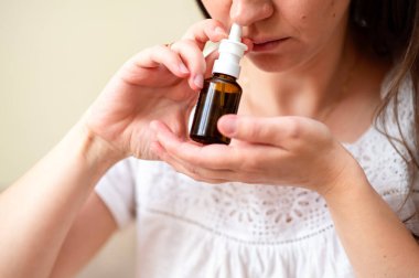 Alerji ya da tıkanıklıktan kurtulmak için burun spreyi kullanan genç kadın, konsept: evde tedavi