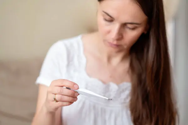 Sıcaklık, konsept, hastalık ve kendini izleme ölçerken soğuk semptomlarına sahip yorgun bir kadının yakın çekimi.