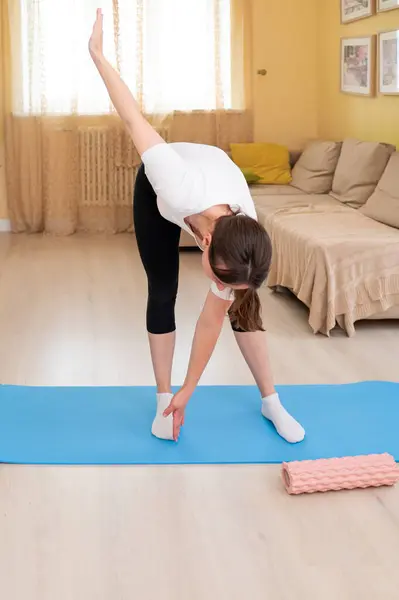 Kadın evde yoga minderinde ısınma egzersizleri yapıyor, antrenmana hazırlanıyor, sağlıklı yaşam tarzı ve ev sağlığı kavramı