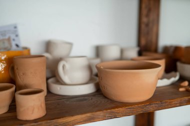 Kırsal ahşap rafta seramik kaplar ve fincanlar seramik kaplar, çömlekçilik stüdyosunun iç dekorasyonu