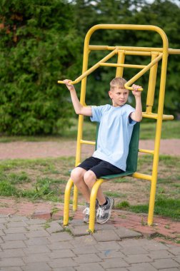 Aktif sarışın genç, yeşil bir parkta sarı spor aletleriyle antrenman yapıyor. Fiziksel aktivitelerden ve taze ai 'den zevk alıyor.