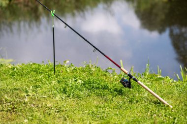 Sakin göl kenarında bir balık oltasına yakın çekim, olta atma, doğada barışçıl bir olta sahnesi.