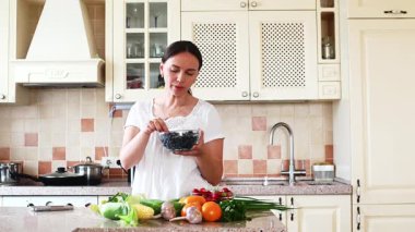 Mutfakta taze meyve ve sebzelerle bir kadın.