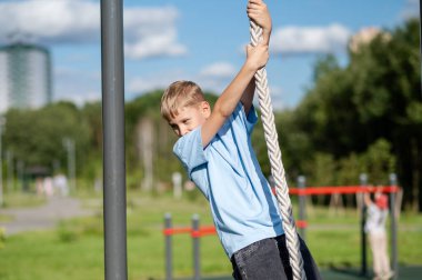 Aktif genç çocuk açık hava spor sahasında ip tırmanışı, spor konsepti, güç ve sağlıklı yaşam tarzı