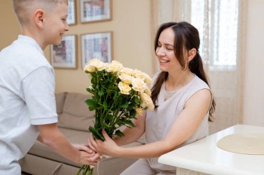 Genç çocuk annesine parlak sarı bir gül buketi hediye eder. Anneler Günü 'nde ya da Uluslararası Kadınlar Günü' nde sevgi ve minnettarlığı kutlar.