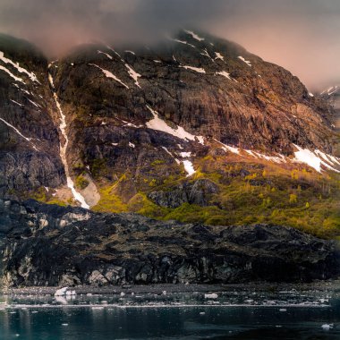 Alaska Buzul Körfezi 'nde bir atlı, bulutların arasından gelen güneş ışığı.