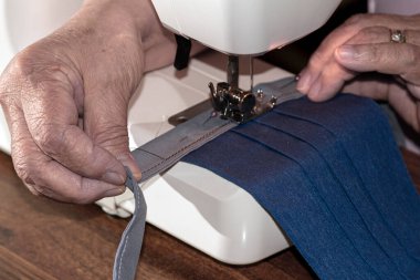 Evde koruyucu maskeler yapan yaşlı bir kişi.