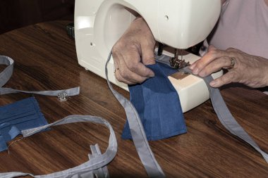 Evde koruyucu maskeler yapan yaşlı bir kişi.