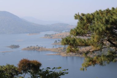Umiam Gölü, Meghalaya 'nın yemyeşil tepeleri arasında, durgun suları gökyüzünü ve çevresindeki yeşillikleri yansıtıyor. Dağlık arazide, sakin bir kaçış ve dokunulmamış doğanın çarpıcı bir görüntüsü sunuyor..