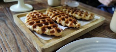 Görüntü, çok güzel bir kaplama kruvasan ve waffle 'ın enfes bir füzyonunu sergiliyor. Eğrinin altın-kahverengimsi, çıtır çıtır bir dış görünüşü var. Derin waffle benzeri oyukları var. Bu da gevreklik ve çıtır çıtır çıtır çıtır bir denge sağlıyor.