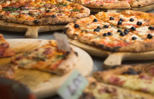 Tahta arka planda farklı pizza çeşitleri var.