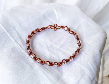 El yapımı beyaz şeffaf boncuklar. Kabloya sarılı bakır mücevherler, beyaz arkaplan.