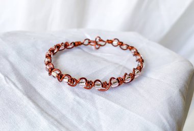 El yapımı beyaz şeffaf boncuklar. Kabloya sarılı bakır mücevherler, beyaz arkaplan.