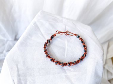 Metalik boncuklu el yapımı bakır bilezik. Kabloya sarılı aksesuarlar, beyaz arkaplan.