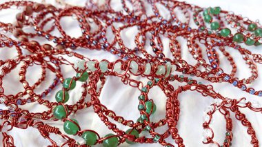 Bir yığın el yapımı bilezik. Kabloya sarılı mücevherler