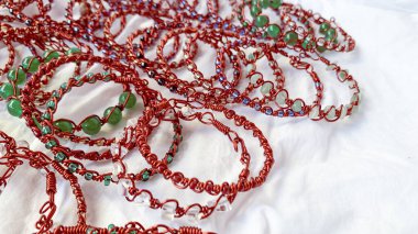 Bir yığın el yapımı bilezik. Kabloya sarılı mücevherler