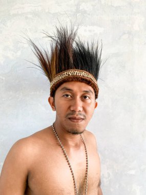 Gömleksiz bir adam sarong giyer ve geleneksel papuan şapkası diker. Cassowary tüyleri ve kolye aksesuarından yapılır..