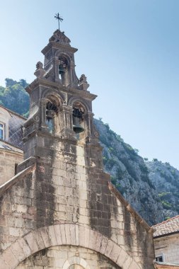 Temiz mavi bir gökyüzünün altında, dağlık bir zemin altında yükselen dekoratif taş çan kulesi kültürel mirası, mimariyi ve huzurlu kırsal manzaraları simgeliyor, zamansız anları ve huzurlu sahneleri çağrıştırıyor..