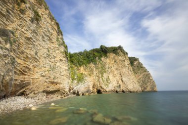 Bereketli bitki örtüsü, berrak mavi su ve güneşli bir gökyüzü altında sakin bir atmosferi olan, doğa severler ve seyahat meraklıları için mükemmel yüksek uçurumların yer aldığı pitoresk bir kıyı manzarası..