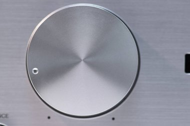 Elektronik bir cihazın gümüş hacim kontrol düğmesinin makro görüntüsü, detaylı dokusunu ve modern tasarımını gösteriyor, teknoloji aygıtlarındaki hassasiyet mühendisliğini ve işlevselliğini gösteriyor.