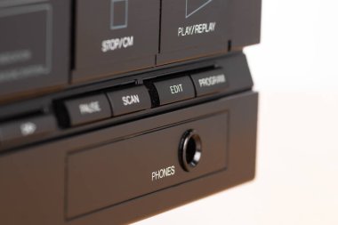 İşlem düğmeleri ve kulaklık takan klasik bir ses sistemi kontrol arayüzünün detaylı görünümü, geçmişe dönük teknoloji ve estetiği vurguluyor.