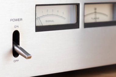 Pürüzsüz metalik yüzeyine, kontrollerine ve ergonomik tasarımına odaklanan bir stereo sistemin gücünün detaylı yakın plan görüntüsü. Modern elektronik ve minimalist teknolojinin mükemmel tasviri.
