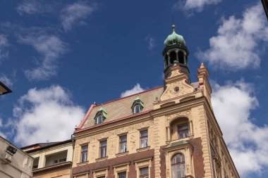 Çarpıcı bir manzara için dağınık bulutlarla aydınlık ve havadar bir gökyüzüne karşı inşa edilmiş, karmaşık bir kuleye sahip tarihi bir bina..