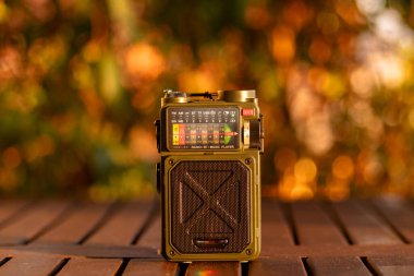 Sıcak, bulanık arka plan ışıklandırmasıyla ahşap bir yüzeye yerleştirilmiş radyo ve müzik çalar nostaljik bir hava yaratıyor..